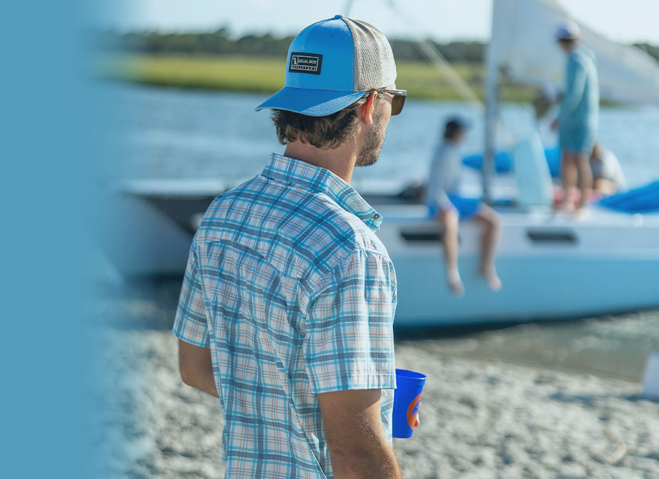 Man wearing local boy outfitters apparel next to a boat